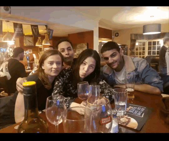 a group of people sitting at a table with a bottle of stella artois on it