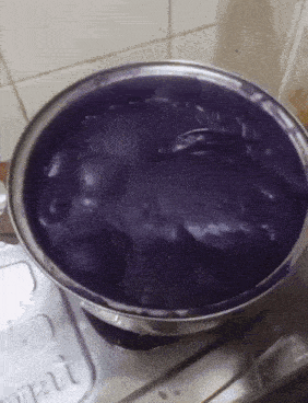 a bowl of purple liquid sits on a stove top next to a container that says " smart "