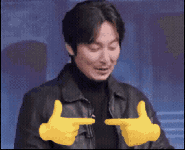 a man wearing a black jacket and yellow gloves is pointing at something