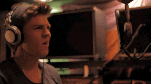a young man singing into a microphone with headphones on