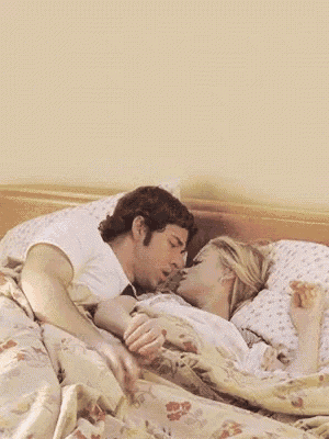 a man in a white shirt is laying on a bed with a woman