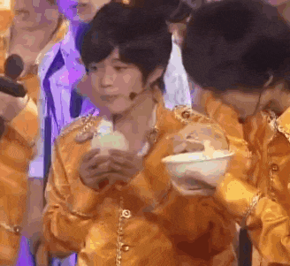 a boy in a yellow shirt is holding a bowl of food in his hand .
