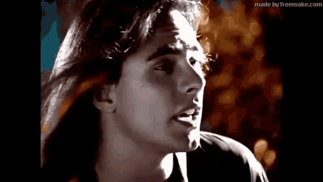 a black and white photo of a young man with long hair .