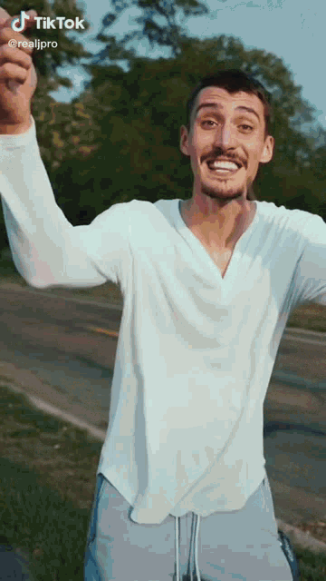 a man wearing a white shirt and blue shorts is holding his hands up in the air ..