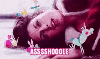 a woman is laying on the floor with a unicorn and rabbits around her and the words assshoooole on the bottom .