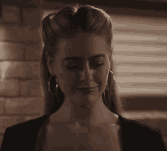 a woman wearing hoop earrings and a black shirt looks down