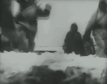 a black and white photo of a group of people walking through the snow .