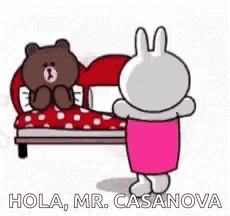 a brown bear and a white bunny are standing next to each other in front of a bed .