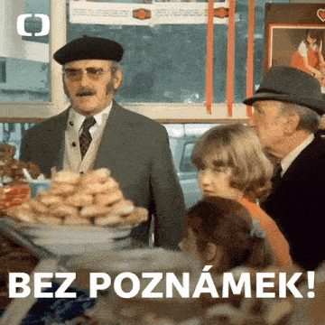 a man in a suit stands in front of a display of donuts with the words bez poznamek written below him