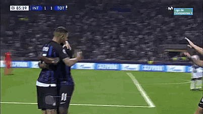 two soccer players hugging on a field with a score of 1 to 1 on the screen