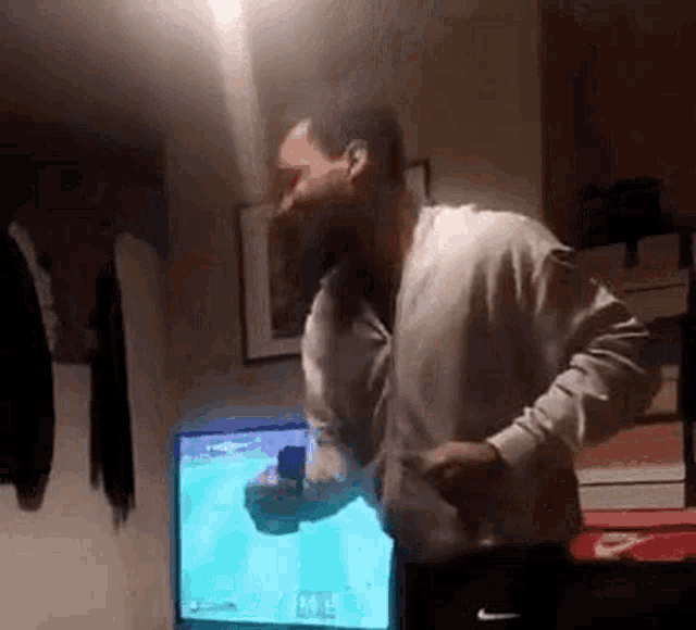 a man is dancing in front of a television while holding a ring in his hand .