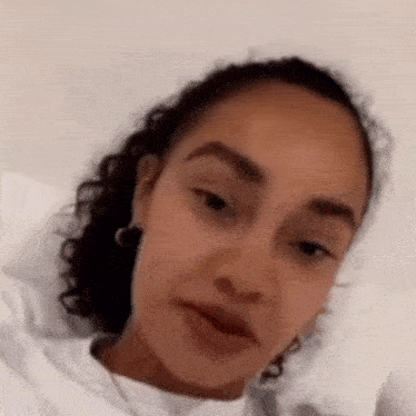a close up of a woman 's face with curly hair and a white shirt .