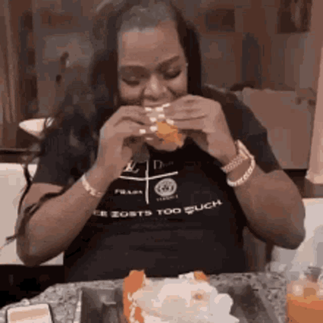 a woman is sitting at a table eating a hamburger and a cake .