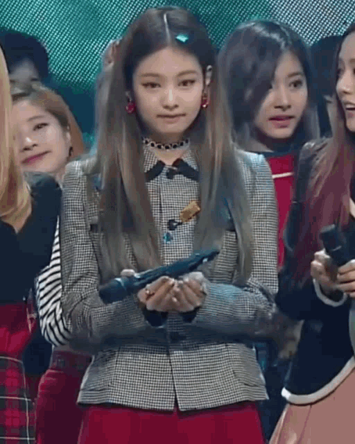 a girl is holding a microphone in her hands while standing in front of a crowd of people .