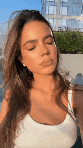 a woman is taking a selfie with her eyes closed .