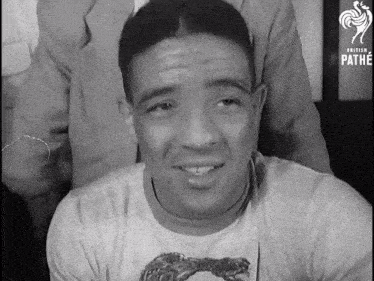 a man wearing a shirt with a horse on it is smiling in a black and white photo