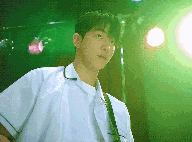 a man in a white shirt stands in front of a green light
