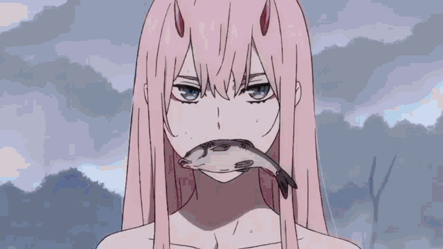 a girl with pink hair is holding a fish in her mouth and looking at the camera .
