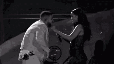 a man and woman are kissing on a stage in a black and white photo .