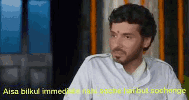 a man with a beard and a bindi on his forehead is talking to someone .