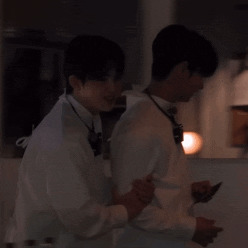 two men are standing next to each other and one is looking at his phone