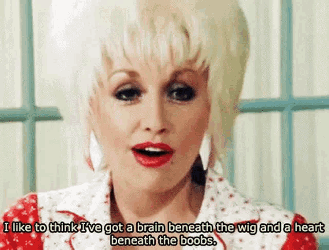 dolly parton is wearing a red and white dress and earrings and is talking about her breasts .