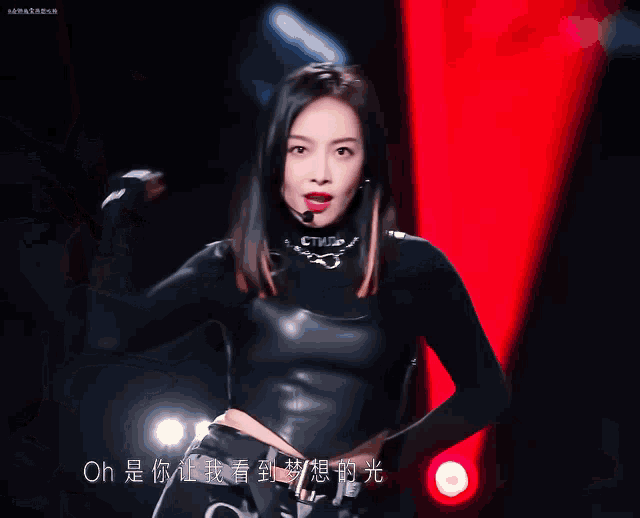 a woman in a black leather outfit stands in front of a red background with the words oh on it