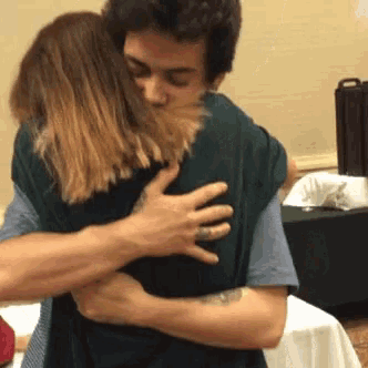 a man and a woman are hugging each other and the woman is wearing a ring on her finger .