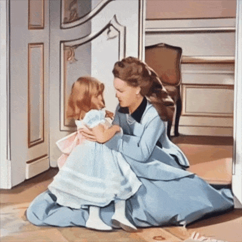 a woman in a blue dress holds a little girl in a room