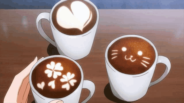 three cups of coffee on a table with hearts and flowers on them