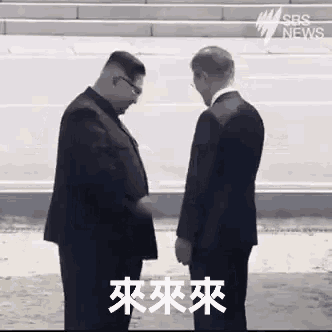 a man in a suit and tie is shaking hands with another man in a suit .