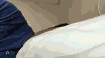 a person in a blue shirt is laying on a bed with a white blanket