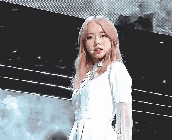 a woman in a white dress stands in front of a black background with the word hybr on the bottom