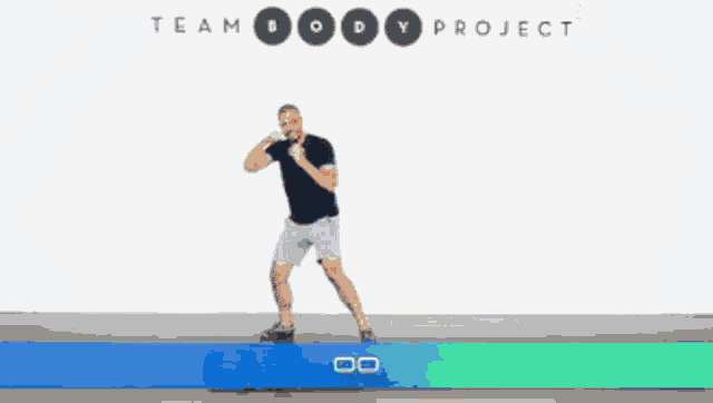 a man is standing in front of a white wall with the word team body project on it