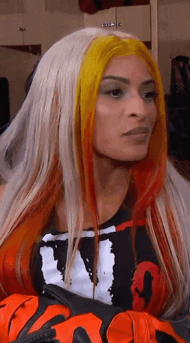a woman with long blonde and red hair is wearing a black and white shirt and gloves .