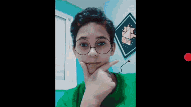 a young boy wearing glasses and a green shirt looks at the camera