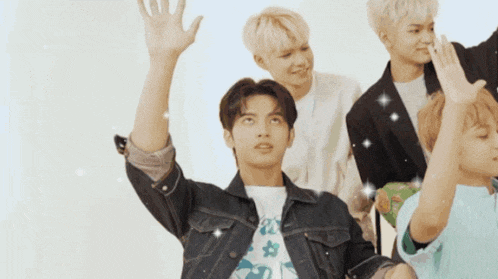 a man in a denim jacket is waving his hand