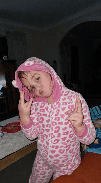 a little girl wearing a pink and white leopard print pajama set making a funny face