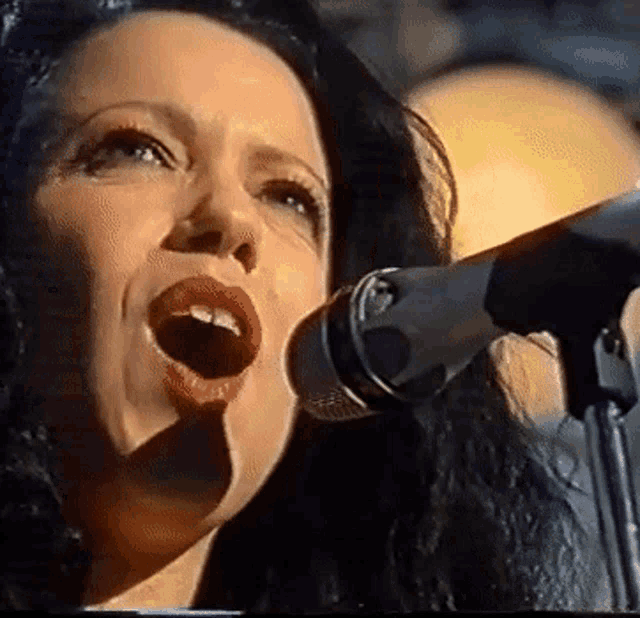 a woman sings into a microphone with her mouth open