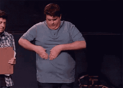 a man is standing on a stage with his hands on his stomach .