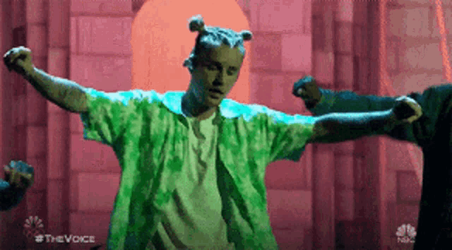 a man in a green shirt is dancing on stage