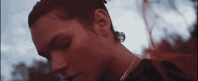 a close up of a man 's face wearing a necklace and earrings .