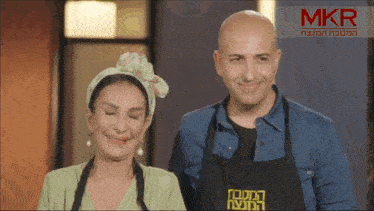 a man and a woman are smiling in front of a mkr ad