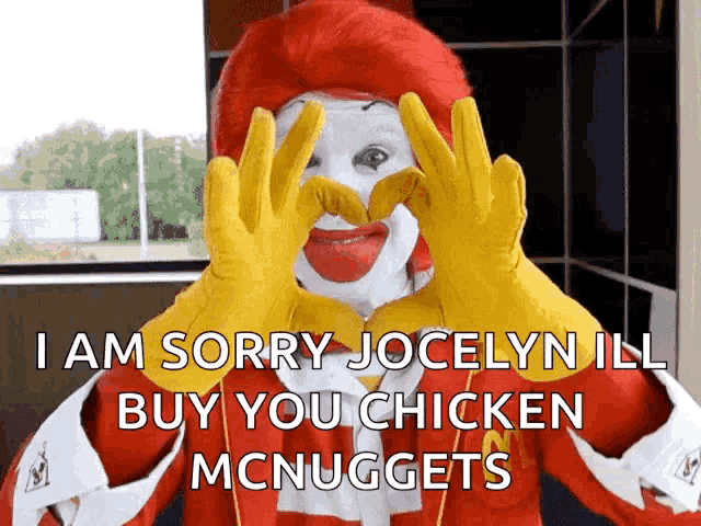 a mcdonald 's clown is making a heart with his hands