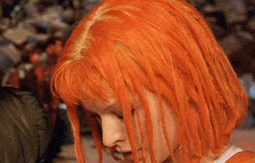 a close up of a woman 's face with bright orange hair