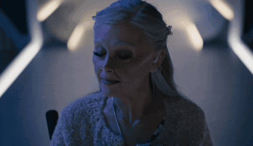 a woman with white hair is sitting in a chair in a dark room