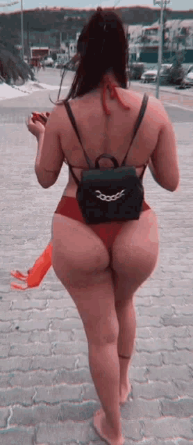 a woman in a bikini is walking down a sidewalk .