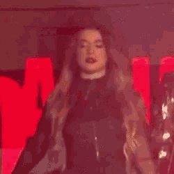 a woman is singing into a microphone on a stage in front of a large red sign that says tru .