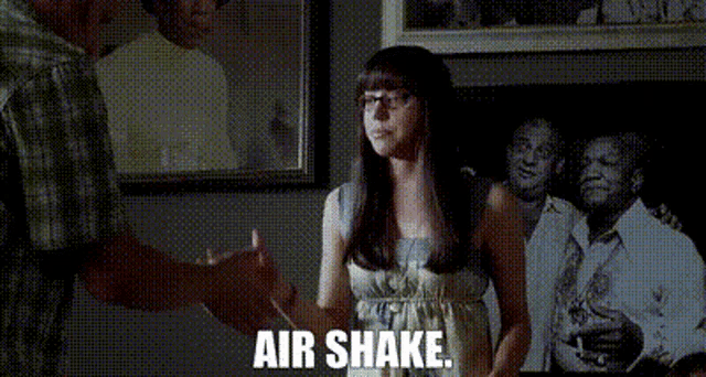 a woman wearing glasses is shaking hands with a man and the words air shake are visible in the background .