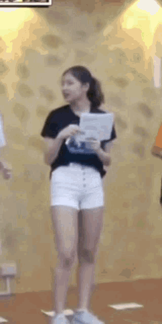 a woman in white shorts and a black shirt is standing in a room .